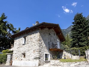 Edifici de pedra amb un balcó, una finestra petita i una xemeneu.