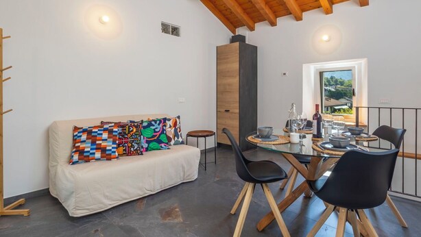 A modern interior with a wooden ceiling, a sofa with colorful cushions, a dining table with chairs, and a view through a window. - Stunning private villa for 4 guests with WIFI, TV, terrace and pets allowed (Piuro)