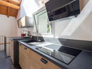 Una cuina moderna amb fogó integrat, una finestra i armaris de fusta.