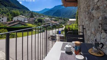 Ein Balkon mit Frühstückstisch, mit Blick auf ein Dorf und Berge.