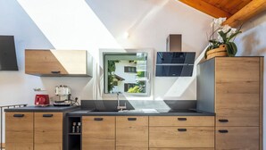 A modern kitchen with wooden cabinets, a built-in oven, and a window overlooking a garden. - Stunning private villa for 4 guests with WIFI, TV, terrace and pets allowed (Piuro)
