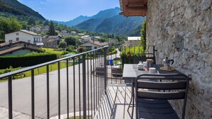 A balcony with a view of a mountain village, a stone wall, and a table with a coffee machine. - Stunning private villa for 4 guests with WIFI, TV, terrace and pets allowed (Piuro)