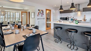 A modern kitchen with a dining area, bar stools, and pendant lighting. - 3 Bed in Holt (oc-ncc46) (Holt)