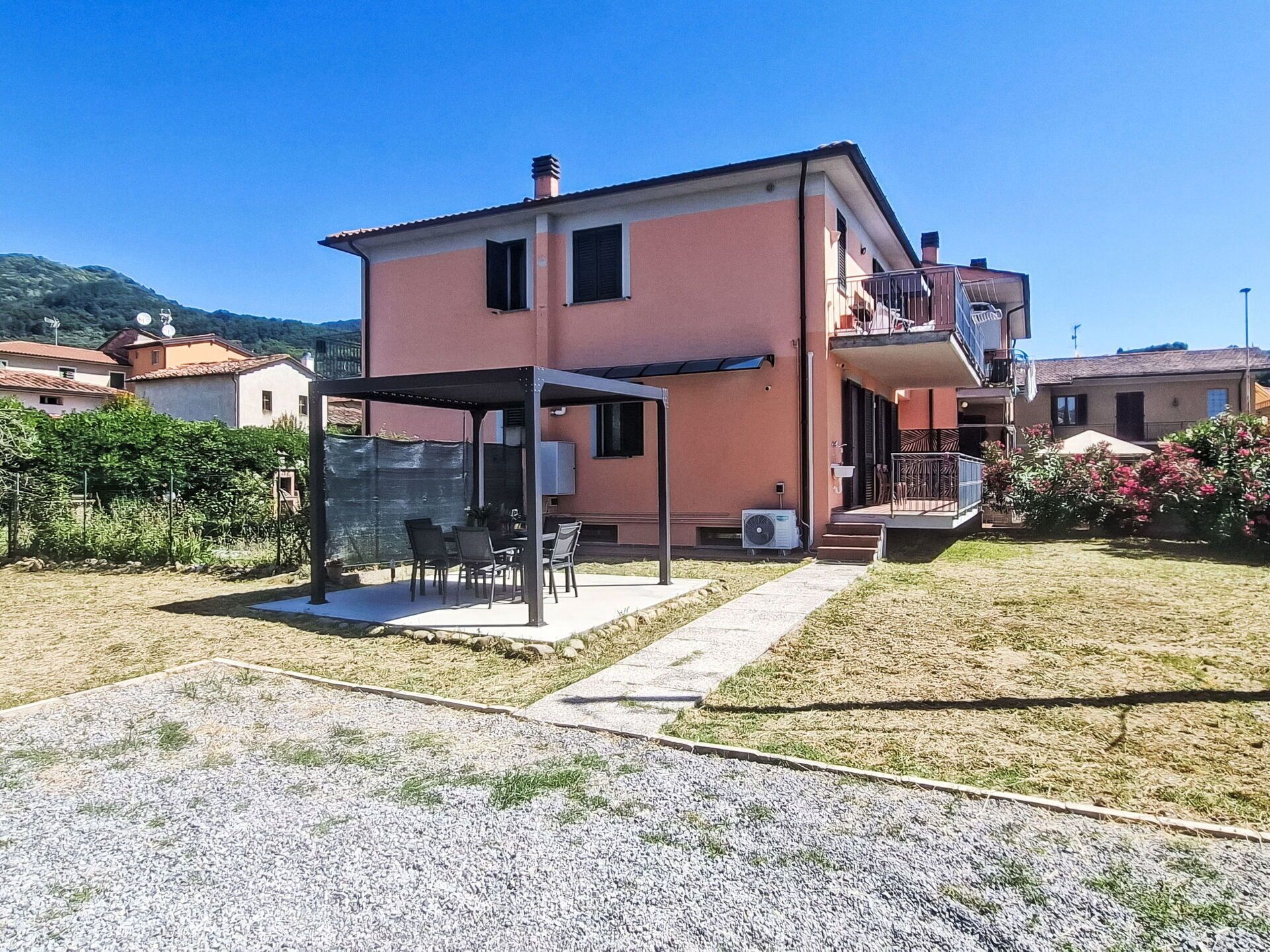 Un bâtiment à deux étages doté d’un patio couvert, d’un espace extérieur aménagé pour s’asseoir et d’un petit jardin.