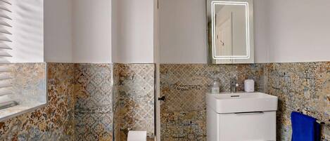 A bathroom with a white sink, mirror, and toilet.