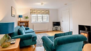 A living room with a sofa set, a television, a fireplace, and a window with a plant. - 2 Bed in Holt (oc-72898) (Holt)