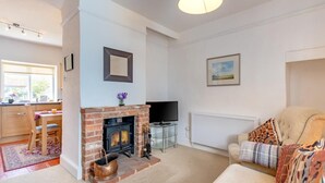 A living room with a fireplace, a television, a sofa, and a dining area. - 2 Bed in Holt (oc-ncc66) (Blakeney)
