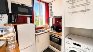 Una cucina compatta con frigorifero, microonde, forno e lavatrice.