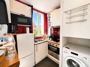 Eine kleine Küche mit Kühlschrank, Mikrowelle, Backofen und Waschmaschine.