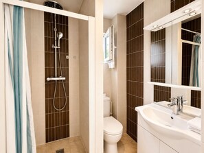 Une salle de bain avec douche, toilettes et lavabo.