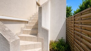 A set of outdoor stairs leading to a building entrance, a wooden fence, and some greenery. - Le Verdun | Paris & Disneyland (Fontenay-sous-Bois)