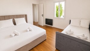 A hotel room with two beds, a TV, a window with a view, and a door leading to another room. - Le Verdun | Paris & Disneyland (Fontenay-sous-Bois)