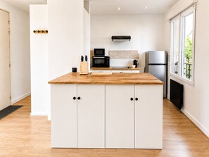 Eine moderne Küche mit weißen Schränken, einer Holz Arbeitsplatte und einer eingebauten Mikrowelle.