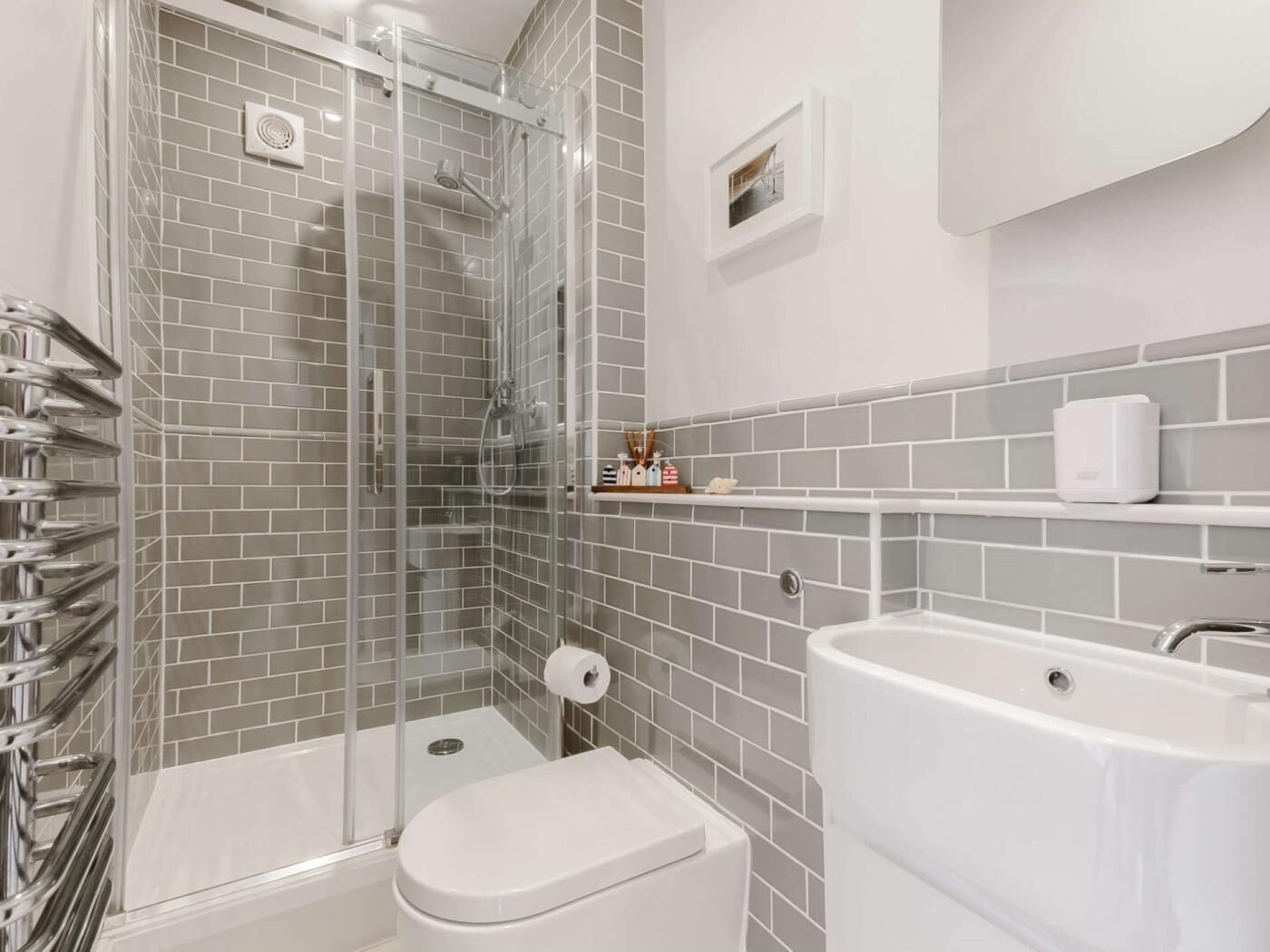 A bathroom with a shower, toilet, and sink, all in white.
