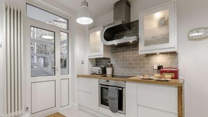 Una cucina moderna con mobili bianchi, forno, microonde e tostapane.
