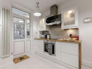 Eine moderne Küche mit weißen Schränken, einem eingebauten Ofen, einer Mikrowelle und einem Toaster.