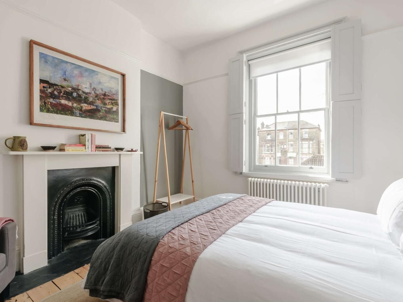 Un dormitorio con cama, chimenea, ventana con vistas y un cuadro en la pared.