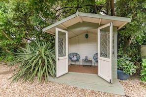 A small, open-sided structure with two chairs and a table, surrounded by greenery. - 3 Bed in Dawlish (oc-72972) (Dawlish)