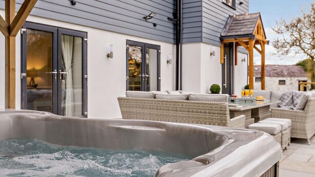 Ett bubbelbad i ett avskärmat utomhusområde, med ett hus i bakgrunden.