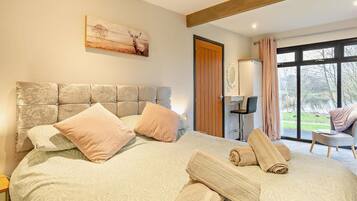 A bedroom with a large bed, a headboard, a painting, a wardrobe, a chair, and a view of the outdoors.
