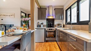 Una cocina moderna con una isla central, electrodomésticos de acero inoxidable y un ventanal que proporciona luz natural.