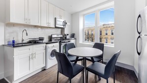 Una cucina moderna con mobili bianchi, forno integrato e zona pranzo con tavolo e sedie rotonde.