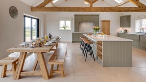 A spacious kitchen with a long wooden table, bar stools, and a central island. - 4 Bed in Bedale (oc-80704) (Newton-le-Willows)