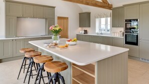 A spacious kitchen with a large island, bar stools, and a built-in oven. - 4 Bed in Bedale (oc-80704) (Newton-le-Willows)