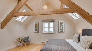 A bedroom with a sloped ceiling, a bed, a chair, a window, and artwork on the walls. - 4 Bed in Bedale (oc-80704) (Newton-le-Willows)