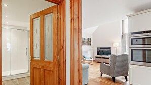 Ein modernes Wohnzimmer mit Fernseher, Sofa und Hocker.