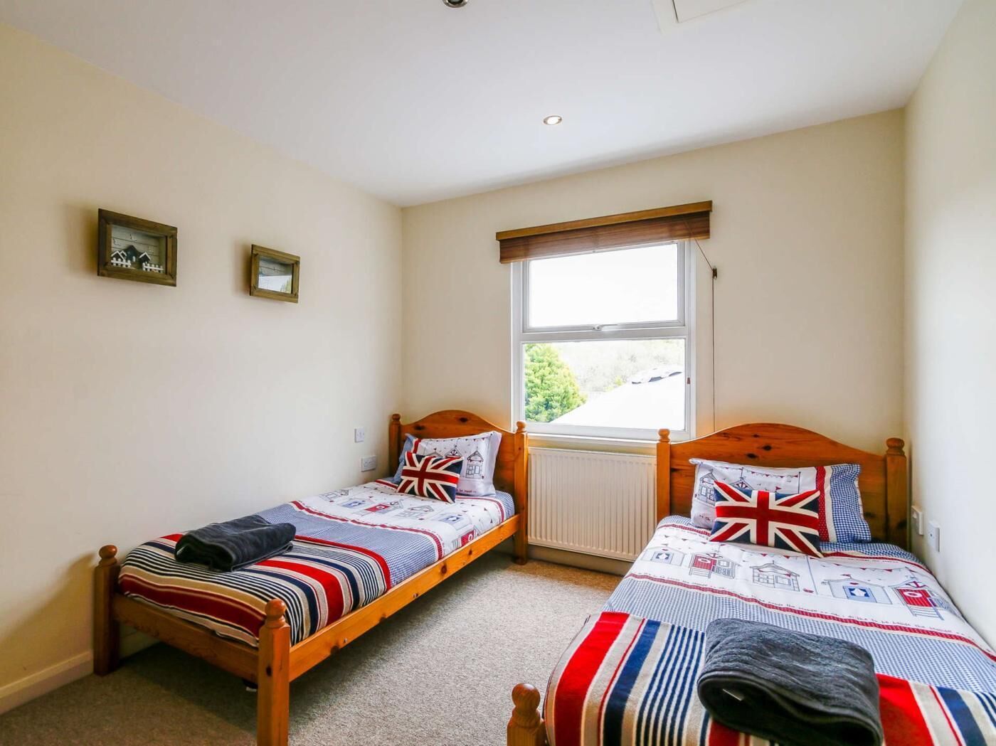 A bedroom with two single beds, a window with a view, and a radiator.