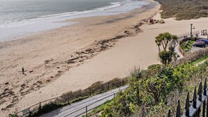 Uma praia costeira com um calçadão pavimentado e um estacionamento.