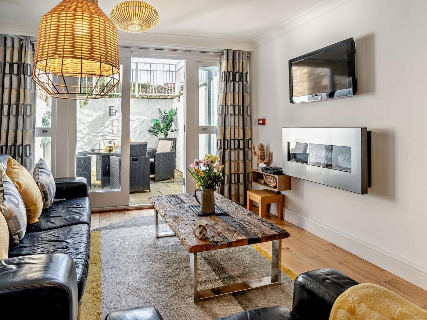 A modern living room with a sofa, a coffee table, a TV, and a view of the outside.