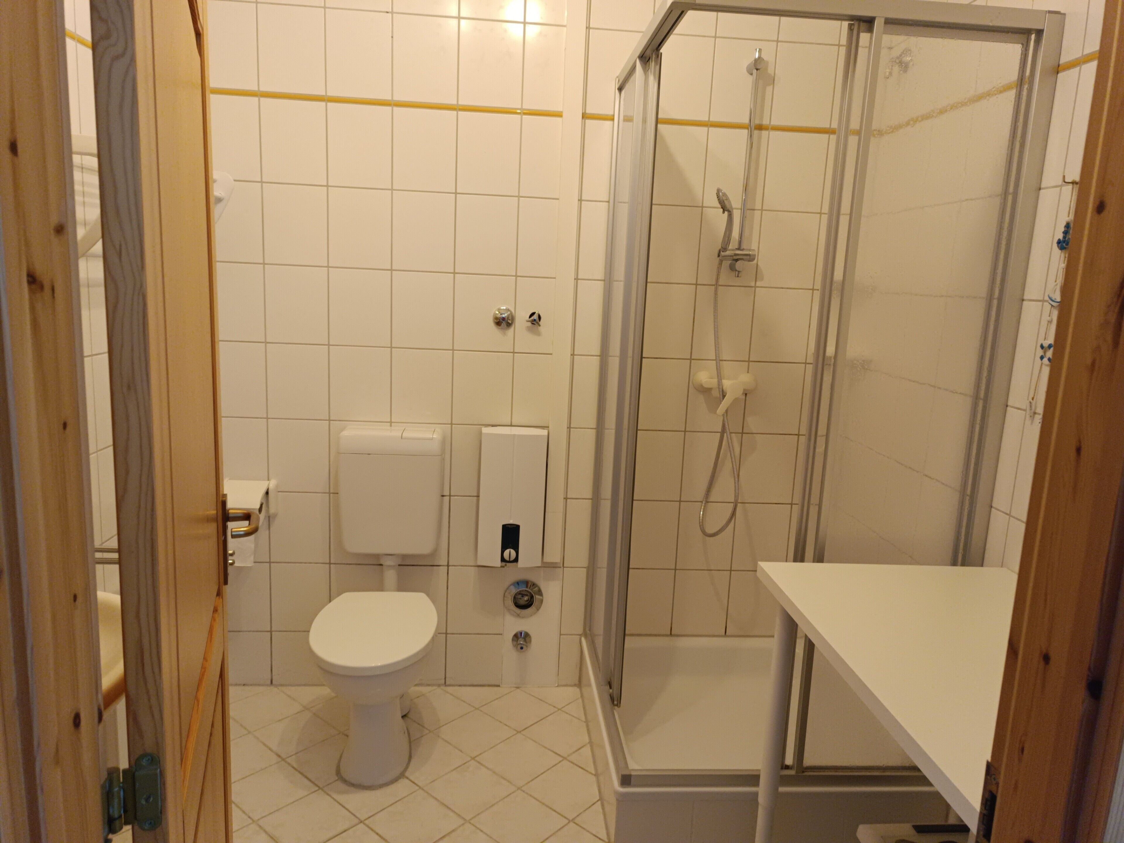 Une salle de bain équipée de toilettes, d’un sèche-mains, d’une douche et d’un lavabo.