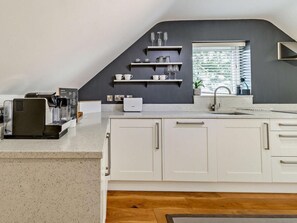 Eine moderne Küche mit weißen Schränken, einer Kaffeemaschine und einem Fenster mit Jalousien.