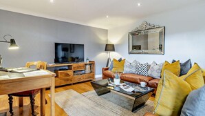 Un salon moderne avec un meuble TV en bois, un canapé en cuir et une table basse.