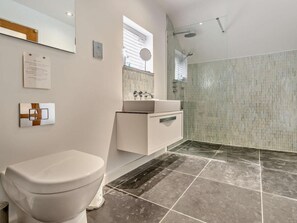 Ein modernes Badezimmer mit Toilette, Waschbecken, Spiegel und Dusche.