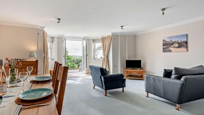 Una sala de estar moderna con comedor, un balcón y vistas panorámicas, y un televisor de pantalla plana.