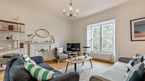 Una sala de estar con chimenea, televisor y un ventanal grande.