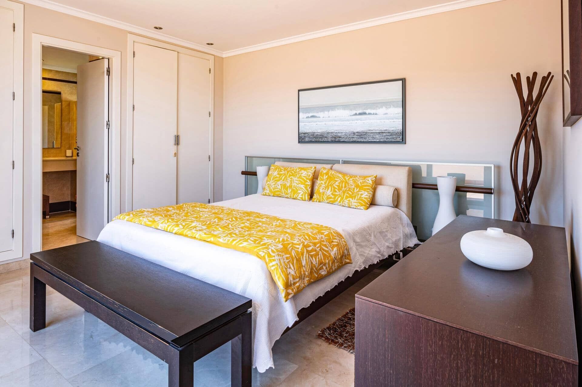 A bedroom with a bed, bedside table, and a mirror.