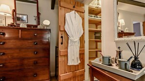 Ein hölzerner Kommode mit Schubladen, ein Bademantel an einer Holztür und ein Spiegel darüber.