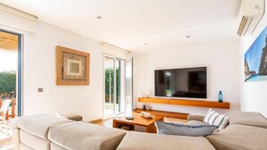 A modern living room with a large flat-screen TV, a wooden coffee table, and a beige sofa. - Villa Nile by Villa Plus (Los Delfines)