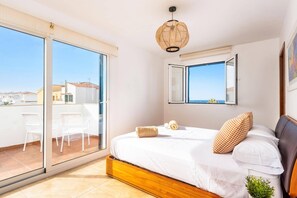 Ein Schlafzimmer mit einem großen Bett, einem Fenster mit Blick, einem Deckenventilator und einem Balkon mit Stühlen.