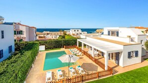 A modern resort with a pool, sun loungers, and a view of the sea. - Villa Nile by Villa Plus (Los Delfines)