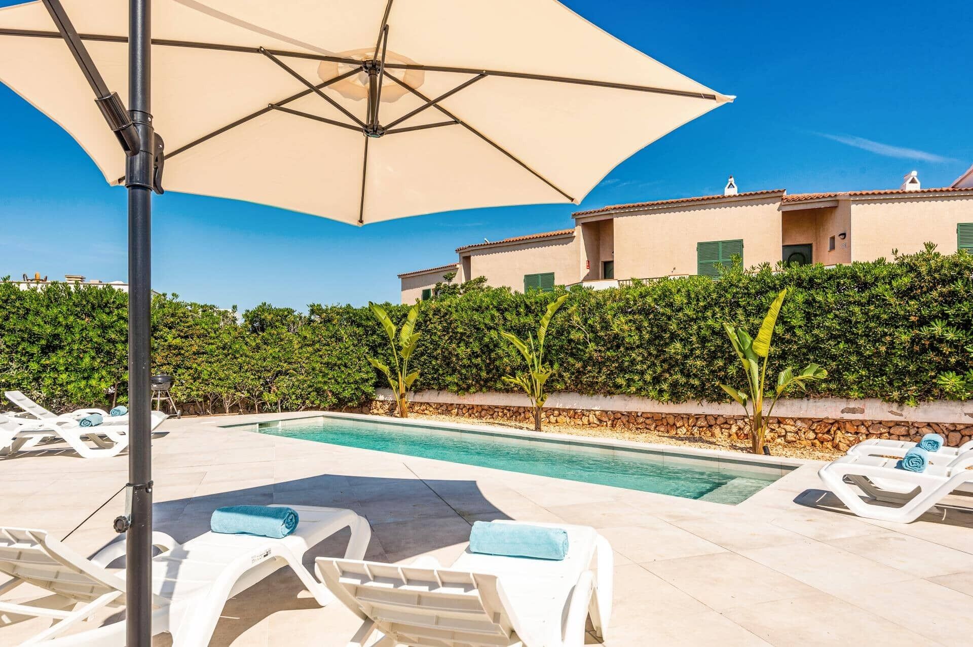 A pool area with lounge chairs and an umbrella.