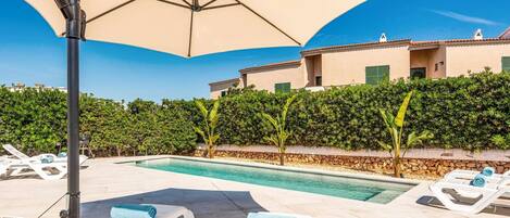A pool area with lounge chairs and an umbrella.