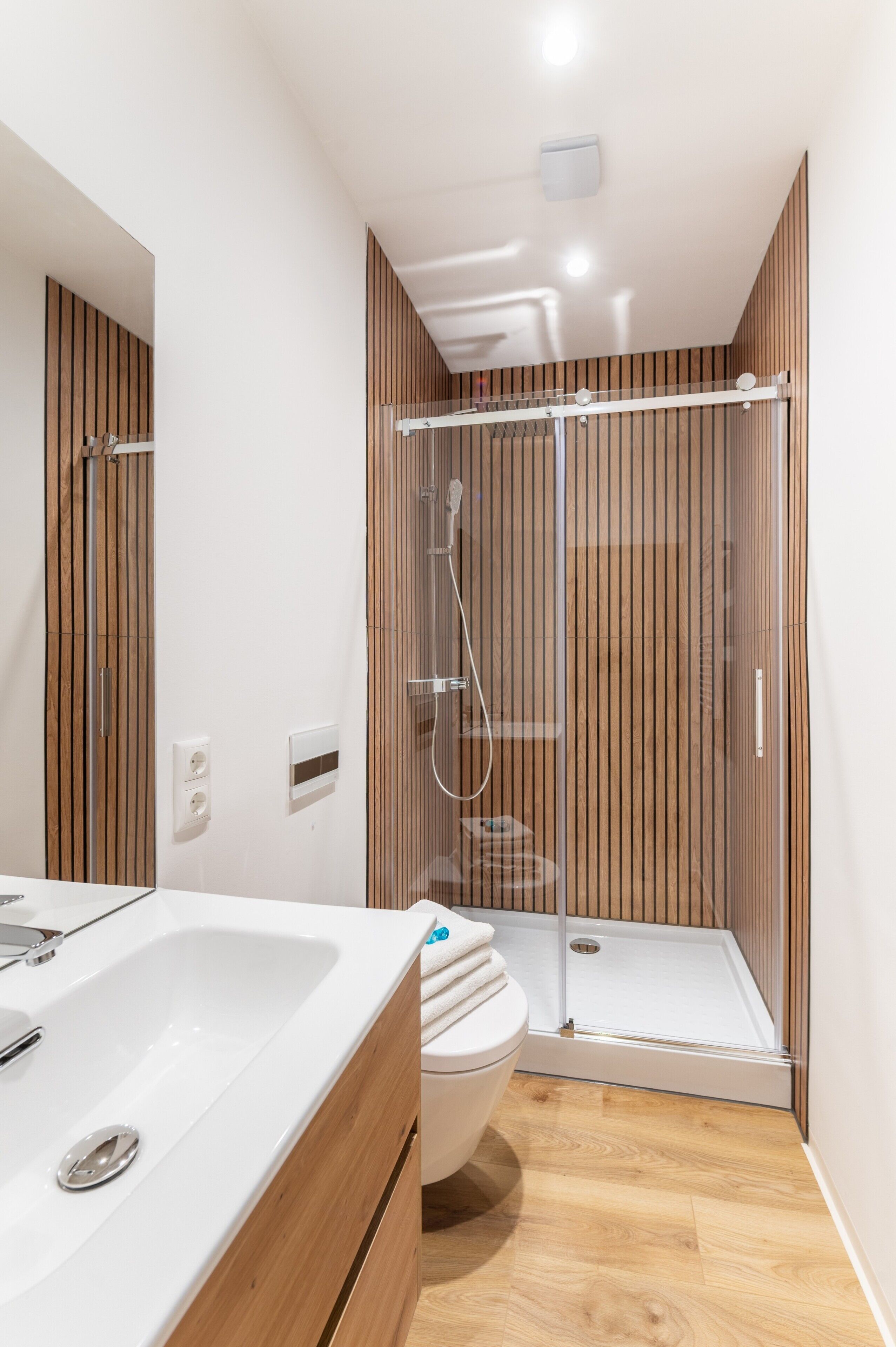 A modern bathroom with a shower, toilet, and sink.
