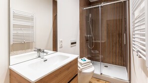 A modern bathroom with a white sink, wooden vanity, and a glass-enclosed shower. - Furnished Apartment Radebeul with Shared Terrace, Garden & Wi-Fi (Radebeul)