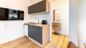 A compact kitchen with a dishwasher, a sink, and a coffee maker. - Furnished Apartment Radebeul with Shared Terrace, Garden & Wi-Fi (Radebeul)