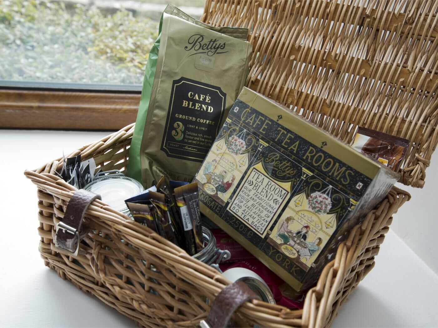 A wicker basket containing a Betty's Café Blend coffee bag, tea room blend tea bags, and a booklet.